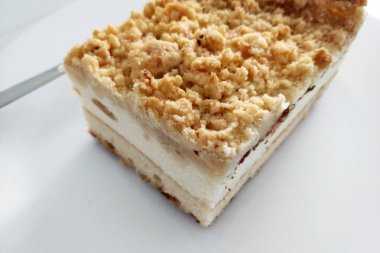 Kalın bir ekmek kırıntısı, kremalı bir orta katman ve hafif, tüylü bir pasta tabanı içeren, beyaz bir arka planda sunulan, tatlı hakkındaki lezzetli detayları geliştirmek için.