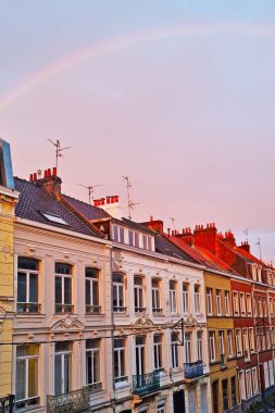 Lille, France, June 23, 2024: Picturesque european street featuring classic row houses under a vibrant sunset sky with a rainbow arching overhead. this captivating scene essence of serene urban beauty, ideal for travel posters, postcards, or wall art clipart