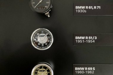 Munich, Germany, August 25, 2024: Detailed display of vintage bmw motorcycle speedometers from models r 61 and r 71 (1930s), r 51 3 (1951-1954), and r 69 s (1960-1962). showcases the evolution of bmw motorcycle dashboards over decades. clipart