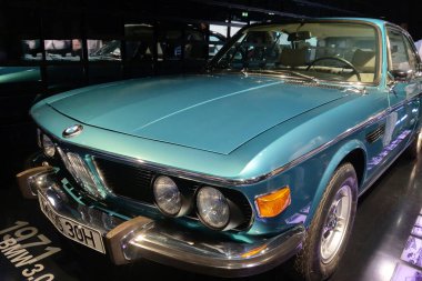 Munich, Germany, August 25, 2024: A pristine 1971 bmw 3.0 cs in a striking teal color showcased at a car exhibition. the classic coupe boasts elegant lines, chrome accents, and distinctive headlamps, epitomizing vintage automotive design and luxury c clipart