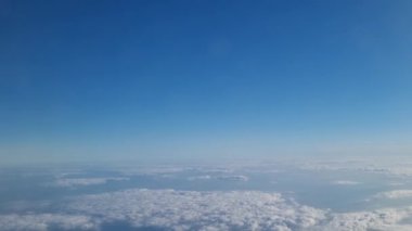 Ufuk boyunca uzanan tüylü, beyaz bulutlarla karışmış geniş mavi gökyüzünü gösteren sakin bir hava sahnesi. Doğa temaları, seyahat promosyonları, arka planlar veya sakin tasarımlar için ideal..