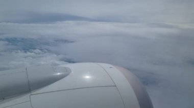 Geniş gökyüzüne karşı uçağın kanadını gösteren, uçaktan gelen beyaz bulutların huzurlu görüntüsü. Seyahat, uçma ve maceranın mükemmel bir temsili, özgürlük duygusunu ve