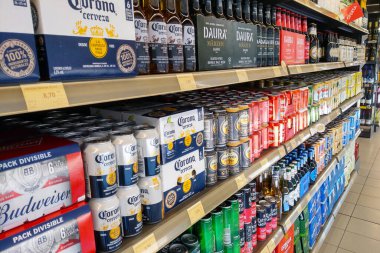 Lloret de Mar, İspanya, 3 Ekim 2024: Corona, Budweiser ve Daura 'nın yer aldığı çeşitli bira markalarıyla dolu bir süpermarket rafı. Kutular ve şişeler, tüketiciler için çeşitli seçenekler ve çeşitli satırlar arasında düzenli olarak düzenlenmiştir..