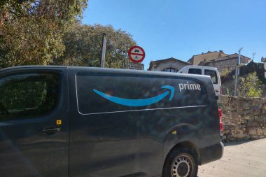 Girona, İspanya, 3 Ekim 2024: Amazon ana dağıtım minibüsü yerleşim mahalline park edilmiş, şehir lojistiği ve ulaşımı sergilenmektedir. Güneşli gün, modern e-ticarette verimli dağıtım hizmetlerinin önemini vurguluyor.