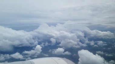 Göz kamaştırıcı hava perspektifi bir uçak penceresinden görülen geniş bir bulut manzarası sergiliyor. Gökyüzünün altında kabarık bulutları, uçmanın ve açık gökyüzünde seyahat etmenin güzelliğini yakalar..