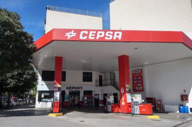 Barselona, İspanya, 1 Ekim 2024: Cepsa benzin istasyonu canlı kırmızı bir gölgelik ve kentsel bir çevrede bulunan birden fazla yakıt pompaları. İstasyonda, yolculara yakıt ve temel olanaklar sunan bir tabela ve bakkal bulunmaktadır..
