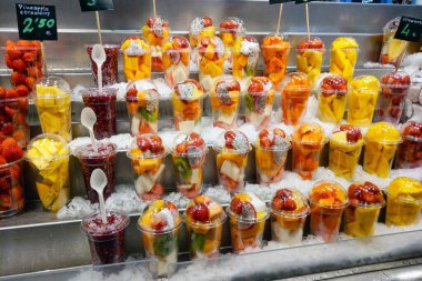 Barselona, İspanya, 1 Ekim 2024: Çilek, ananas ve mango gibi çeşitli rengarenk meyvelerin sergilendiği ve kaşıklarla sergilenen taze meyve tabakları sergilenmektedir. Yaz atıştırmalıkları ve sağlıklı yemek için ideal.