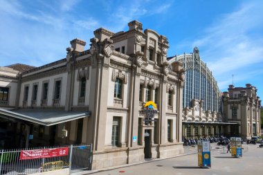 Barselona, İspanya, 1 Ekim 2024: Güzel korunmuş tarihi bir tren istasyonu, canlı mavi gökyüzü altında karmaşık mimari tasarımı sergiliyor. Binanın klasik cephesi ve büyük pencereleri zamansız zarafet ve ulaşım mirasını yansıtıyor.