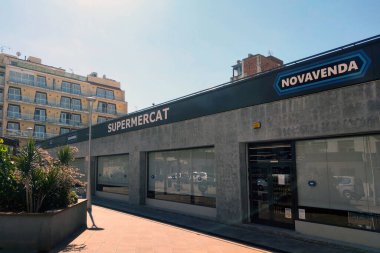 Lloret de Mar, Spain, October 4, 2024: Modern supermarket exterior with a contemporary urban design. highlights clean lines and minimalist architecture amidst city buildings. ideal for retail, architecture, and urban development themes. clipart