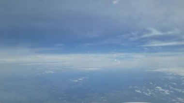 Uçsuz bucaksız mavi gökyüzünü ve dağınık bulutları gösteren sakin bir hava sahnesi. Ufuk kusursuz bir şekilde atmosferik katmanlara karışıyor, yukarıdan barışçıl ve geniş bir manzara yaratıyor..