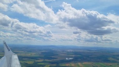 Wroclaw, Polonya, 18 Haziran 2024: Uçsuz bucaksız bir arazinin üzerinde ryanair kanat gösteren nefes kesici bir hava manzarası, aşağıdaki tarlaların mozaiği ve dağınık bulutlu parlak mavi bir gökyüzü