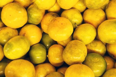 Canlı renklerini ve doğal dokularını gösteren taze sarı ve yeşil limonların renkli bir görüntüsü. Mutfak teması, mutfak dekorasyonu ve yemekle ilgili fotoğrafçılık için ideal, tazelik ve canlılık vurgulanıyor.