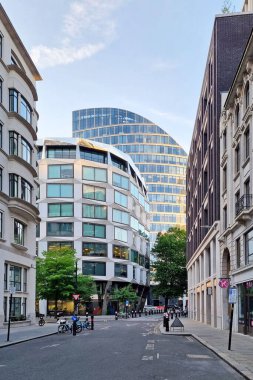Londra, Birleşik Krallık, 28 Haziran 2024: Canlı bir şehir caddesinde modern ve klasik mimarinin karışımını keşfedin. Yayaların, bisikletçilerin ve park halindeki araçların üzerinde şık tasarım kulesi olan yüksek binalar dinamik kentsel yaşam tarzını gösteriyor..