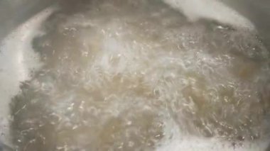 Kaynayan su, paslanmaz çelik bir tencerede hızla kaynıyor. Enerjik bir hareket ve ısı sergiliyor. Mutfak ve mutfakla ilgili projeler için mükemmel. Sahne ısıtılmış suyun dinamik doğasını vurguluyor.