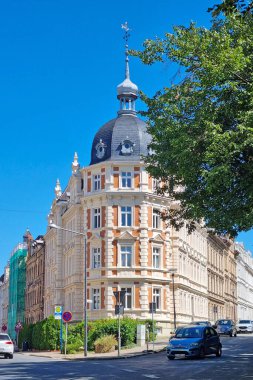 Goerlitz, Almanya, 6 Temmuz 2024: Klasik mimari detaylarla süslenmiş güzel bir tarihi bina açık mavi bir gökyüzünün altında duruyor. Sakin bir caddede bulunan ve yemyeşil arabaların karışımı Avrupa kentsel cazibesini somutlaştırıyor..