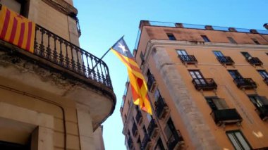 Girona, İspanya, 3 Ekim 2024: Katalan bağımsızlık bayrağının şehir sahnesi açık mavi gökyüzüne karşı tarihi bir binadan örtülmüş, geleneksel mimari ve modern siyasetin karışımı