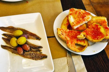 Ançüezli Akdeniz aperatifi bir porsiyon zeytin ile servis tabağında canlı domates bruschetta ile birlikte. Gurme yemek için mükemmel. Lezzet ve dokuların karışımı sergileniyor..