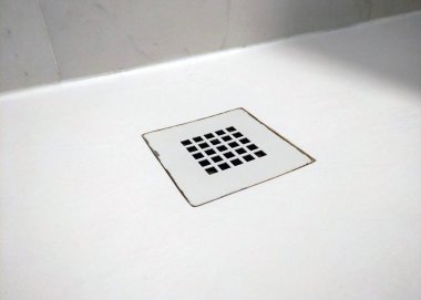 Merkezinde temiz, kare bir drenaj olan beyaz duş zemininin olduğu minimalist bir banyo. Tasarım, basitlik ve işlevselliği vurgular, modern, çağdaş iç mekanlar için mükemmeldir..