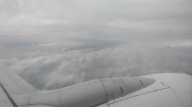 Geniş, kabarık bulutlar arasında kanadı gösteren bir uçak penceresinden sakin bir manzara. Bulutlu gökyüzü sakin ve huzurlu bir atmosfer yaratır. Seyahat ve havacılık temalı tasarımlar için idealdir.