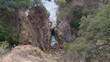 Dramatik bir dağ geçidi, verimli yeşilliklerle çevrili engebeli uçurumları kesen çağlayan bir dereyi gözler önüne seriyor. Doğa temalı fotoğrafçılık için ideal, bu sakin manzara ham güzelliği vurgular.