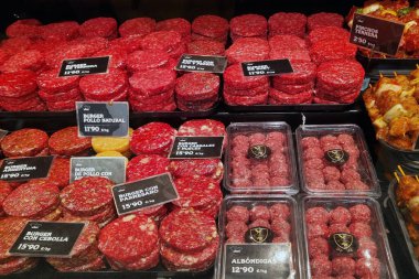 Barselona, İspanya, 1 Ekim 2024: Bir gurme kasap dükkanında çeşitli yeni hazırlanmış hamburgerler ve et ürünleri sergilenmektedir. Sergide sığır eti, tavuk ve aromalı hamburgerlerin yanı sıra düzgün paketlenmiş köfteler de yer alıyor.