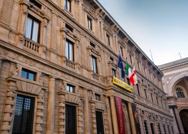Milan, İtalya, 1 Aralık 2024: Milano 'da Palazzo Marino, karmaşık taş işçiliği ve sıra sıra pencerelerle Rönesans mimarisi sergiliyor. Ön cephe, belediye binası olarak önemini vurgulayan birden fazla bayrakla süslenmiştir..