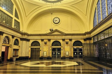 Barcelona, Spain, October 1, 2024: Grand hall of a historic train station featuring exquisite architectural design, arched windows, and a central clock. the elegant interior is highlighted by intricate detailing and a spacious layout, conveying a tim clipart