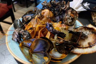 Midye, yengeç ve karides gibi çeşitli okyanus lezzetlerinden oluşan canlı bir deniz ürünleri tabağı. Aşçılık meraklıları için mükemmel, bu yemek zengin dokular ve taze kabuklu deniz ürünleri mutfağı renkleri.