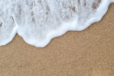 Yumuşak dalgalar, kumlu sahille buluştuklarında köpüklü desenler oluşturur. Sakin kıyı şeridi sahnesi, su ve kumun rahatlatıcı etkileşimi, huzur ve rahatlamayı çağrıştırıyor, seyahat ve doğa temaları için mükemmel..