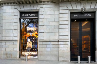 Barselona, İspanya, 25 Aralık 2024: Lüks bir louis vuitton butiği şık tasarımların yer aldığı göz alıcı bir vitrin sergisi sergiliyor. Dış yüzeyde, sofistike bir tasvir ile yüksek kaliteli materyallerle klasik mimari yer almaktadır. 