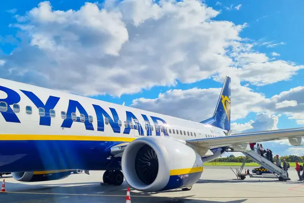 Wroclaw, Polonya, 29 Eylül 2024: Parlak bir günde pistte bir ryanair uçağına binen yolcular. Mavi gökyüzü ve dağınık bulutlar modern hava yolculuğunun konforu ve ulaşılabilirliği için davetkar bir atmosfer yaratıyor..