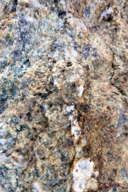 Kaya yüzeyinin yakın plan görüntüsü karmaşık desenler ve toprak renkler sergiliyor. Doğal güzelliği ve eşsiz jeolojik özellikleri vurgulayarak, arka planda, tasarım projelerinde ve doğa temalı sanat eserlerinde kullanmak için ideal.