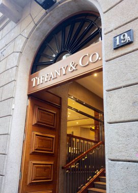 Milan, İtalya, 2 Aralık 2024: Lüks mücevher markasının zarif vitrininde büyük ahşap bir kapı ve güzel kıvrımlı bir pencere bulunmaktadır. Giriş tarihi bir eserde ayrıcalık ve üst düzey moda cazibesi yayar. 