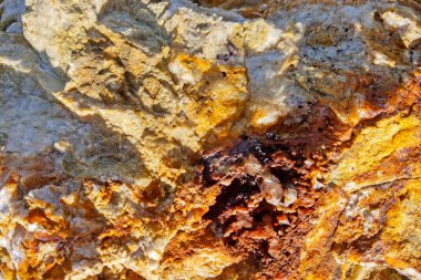 Canlı bir kaya yüzeyinin yakın görüntüsü, zengin bir doku ve renk karışımı, jeolojik bileşim ve mineral çeşitliliği içerir. Eğitim, tasarım ve sanatsal uygulamalar için mükemmel.