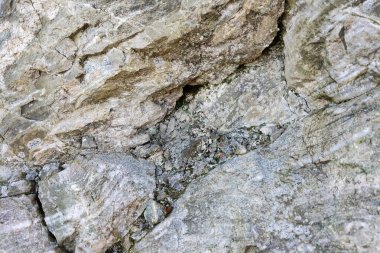 Doğal bir kaya yüzeyinin detaylı görüntüsü karmaşık dokular ve hava durumu sergiliyor. Arkaplan için ideal, bu taş desen tasarım projeleri için kırsal ve organik bir his sunuyor..