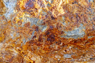Canlı turuncu, kahverengi ve gri tonlara sahip desenli doğal kaya yüzeyinin yakın görüntüsü. Karmaşık şablonlar ve mineral oluşumları onu arka planlar, eğitim materyalleri ve jeolojik araştırmalar için ideal hale getirir..