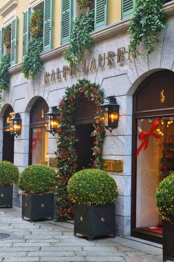 Milan, İtalya, 2 Aralık 2024: Zarif bir Ralph Lauren mağazası şık Noel süslemeleri ile süslenmiş, yemyeşil, şenlikli çelenkler ve parlak ışıklarla süslenmiş. Büyük pencereler tatil temalı görüntüler sergiliyor, samimi ve davetkar bir ortam yaratıyor