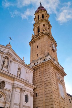 Zaragoza, İspanya, 27 Aralık 2024: Karmaşık bir cephesi ve uzun, süslü bir kulesi olan tarihi bir kilise açık mavi gökyüzüne karşı görkemli bir şekilde ayakta duruyor. Mimari ayrıntılar kültürel ve tarihi simgeleri sembolize ederek klasik tasarım elementlerini yansıtır.