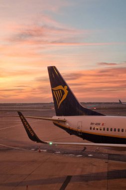 Barselona, İspanya, 4 Ocak 2025: Bir ryanair uçak kuyruğu havaalanında çarpıcı bir günbatımı arka planına çarpıyor. Sakin gökyüzü, pistle birlikte, bir seyahat heyecanı ve macera hissi uyandırır, havacılık ve seyahat için idealdir.