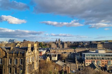 Edinburgh, İskoçya, 30 Mart 2025: Tarihi bir şehir manzarasının çarpıcı bir görüntüsü, eski ve modern mimarinin canlı mavi gökyüzü altında dağınık bulutlar altında bir karışımını sergiliyor. Görüntü, genişleyen bir Kİ 'deki kentsel ahenk ve kültürel mirası vurguluyor