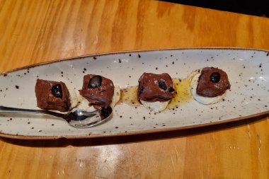 Zengin çikolatalı tatlı uzun bir tabakta zarif bir şekilde hazırlandı, kahve çekirdekleri ile süslenmiş koyu çikolata parçaları ve kremayla servis edildi. Davetkar bir sunum için bir kaşık yanında durur.