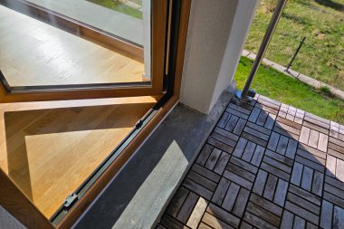 Modern balkon geometrik kiremit desenli ahşap döşeme içeriyor, sürgülü kapılı iç alana sorunsuz bir şekilde bağlı. Balkon yeşil bir manzaraya bakıyor, doğal elementleri çağdaş tasarım ile harmanlıyor, kentsel ret için mükemmel.