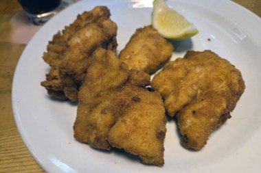 Altın, kızarmış tavuk parçaları beyaz bir tabakta ustalıkla düzenleniyor ve yanında da limon dilimi var. Bu iştah açıcı yemek, her yemek için mükemmeldir. Çekici dokusunu ve lezzetli tadını ön plana çıkarır..