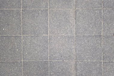 Kalıplı gri beton döşeme kiremitlerinin yukarıdan görünüşü, şebeke şablonuyla vurgulanmış. Üniforma çizgileri ve ince dokusu mimari ve iç tasarımlar için modern ve temiz bir yüzey sağlar..