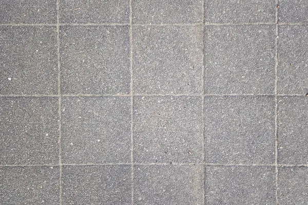 Kalıplı gri beton döşeme kiremitlerinin yukarıdan görünüşü, şebeke şablonuyla vurgulanmış. Üniforma çizgileri ve ince dokusu mimari ve iç tasarımlar için modern ve temiz bir yüzey sağlar..