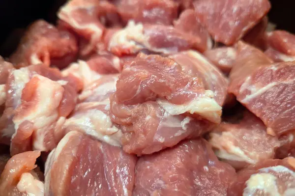 Yakın plan taze çiğ domuz eti parçaları doğal mermer ve doku içeriyor. Izgara, kızartma ya da güveç gibi yemek kullanımları için mükemmel. Tazelik ve kaliteyi vurguluyor, besin sunumları ve yemek rehberleri için ideal.