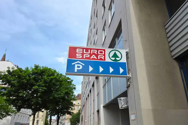 Viyana, Avusturya, 3 Mayıs 2025: Eurospar mağaza tabelası ve şehir mimarisinin ortasında park talimatları. Modern bir şehir ortamında mavi bir gökyüzü arkaplanı, ağaçlar ve kentsel unsurlar, tüketici alışveriş yerleri ve perakende navigasyonu yer almaktadır..
