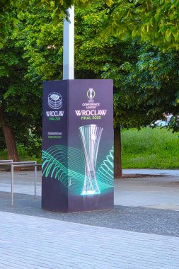 Wroclaw, Polonya, 23 Mayıs 2025: 2025 Uefa Konferans Ligi Wroclaw finalini sergileyen bir şehir parkında dikey reklam paneli. Tasarım, verimli yeşillik ve şehir sporları coşkusu ile çevrili turnuva kupasını ön plana çıkarıyor..
