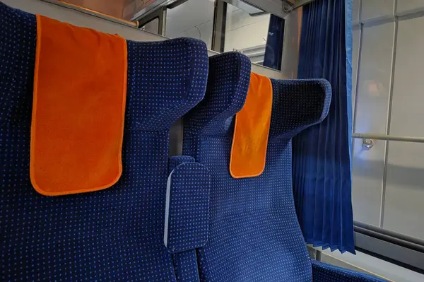 Canlı turuncu başlık kapaklı mavi döşemeli koltukların olduğu bir tren kulübesinin içinde. Sahne bir rahatlama ve rahatlama hissi uyandırıyor. Uzun mesafe seyahati için ideal. yumuşak ışıklandırma modern tasarıma sıcaklık katar.