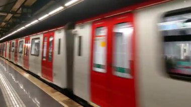 Barselona, İspanya, 2 Ocak 2025: Kırmızı metro treni bir yeraltı istasyonundan hızla geçerek şehir içi ulaşımın dinamik özünü yakalıyor. Bulanık hareket hızı, verimliliği ve şehir hayatının hareketli ritmini vurgular..
